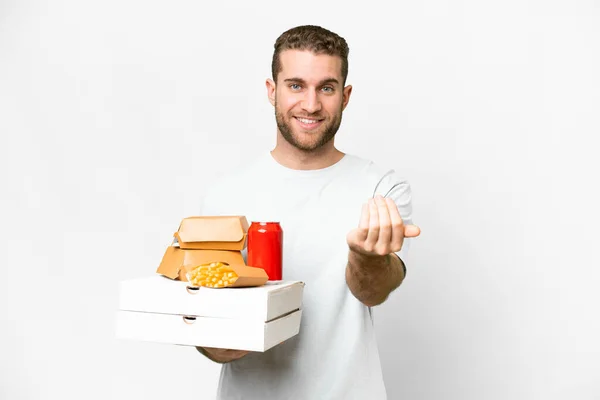 年轻英俊的金发男子举着比萨饼和汉堡包 与孤立的背景邀请手拉手 很高兴你来了 — 图库照片