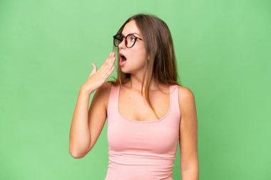 Genç ve güzel bir kadın izole edilmiş arka planda esniyor ve elleriyle ağzını kapatıyor.