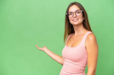 İzole edilmiş arka planda genç ve güzel bir kadın. Davet edilmek için ellerini yana uzatıyor.