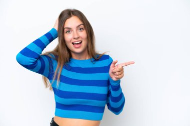 Beyaz arka planda izole edilmiş genç beyaz kadın şaşırmış ve işaret ediyor.