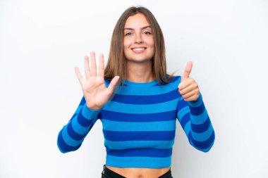 Beyaz arka planda izole edilmiş beyaz tenli genç kadın parmaklarıyla altısını sayıyor.