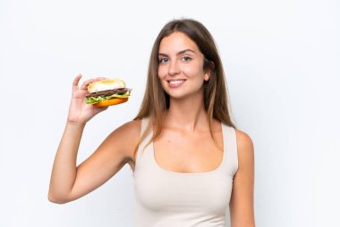 Beyaz arka planda izole edilmiş bir burger tutan genç ve güzel bir kadın.