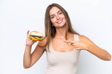 Beyaz arka planda izole edilmiş bir burger tutan genç ve güzel bir kadın.
