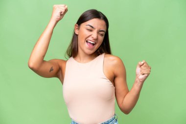 Young caucasian woman isolated on green chroma background celebrating a victory