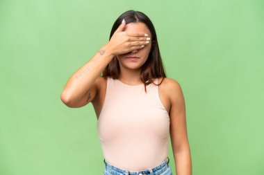 Young caucasian woman isolated on green chroma background covering eyes by hands. Do not want to see something