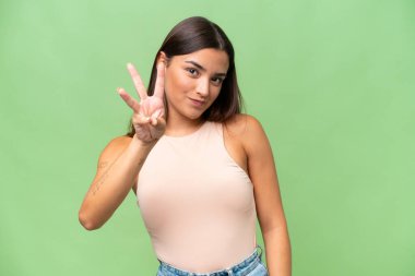 Young caucasian woman isolated on green chroma background happy and counting three with fingers