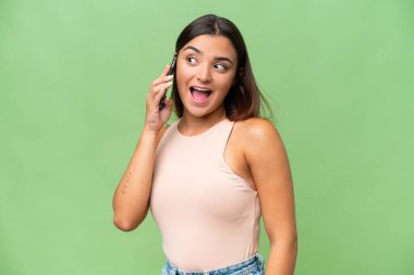 Young caucasian woman isolated on green chroma background keeping a conversation with the mobile phone