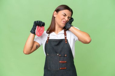 Butcher woman wearing an apron and serving fresh cut meat isolated on green chroma background frustrated and covering ears
