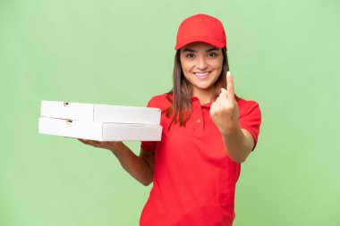 Pizza delivery caucasian woman with work uniform picking up pizza boxes isolated on green chroma background doing coming gesture