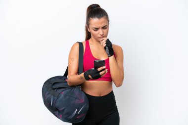 Young sport woman with sport bag isolated on white background thinking and sending a message