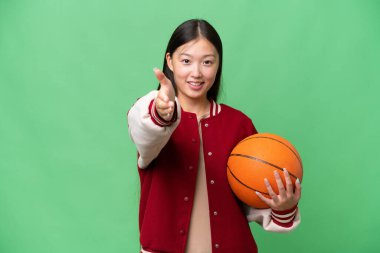 Young basketball player asian woman over isolated background shaking hands for closing a good deal