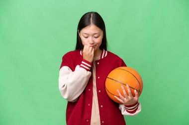 Young basketball player asian woman over isolated background having doubts