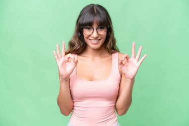 İzole edilmiş arka planda beyaz bir kadın iki eliyle tamam işareti gösteriyor.