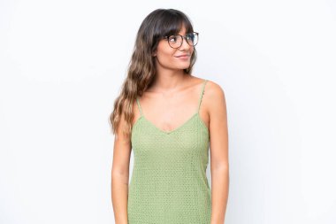 Beyaz arka planda izole edilmiş genç beyaz kadın yan bakıyor ve gülümsüyor.