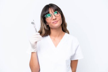 Beyaz arka planda izole edilmiş aletler tutan beyaz dişçi kadın.