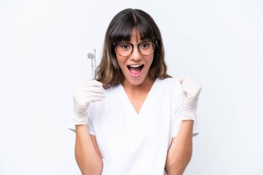 Dentist caucasian woman holding tools isolated on white background celebrating a victory in winner position