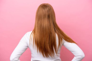 Genç kızıl saçlı kadın arka planda pembe arka planda izole edilmiş.