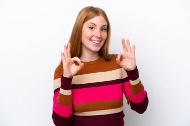 Beyaz arka planda izole edilmiş genç kızıl saçlı kadın iki eliyle onay işareti gösteriyor.