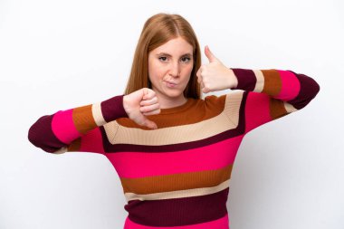 Genç kızıl saçlı kadın beyaz arka planda izole edilmiş, iyiye-kötüye işaret yapıyor. Evet ya da hayır arasında kararsız