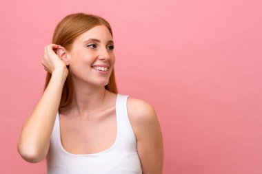 Genç kızıl saçlı kadın pembe arka planda izole edilmiş.