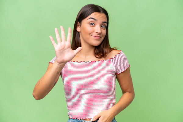 Young caucasian woman isolated on green chroma background counting five with fingers