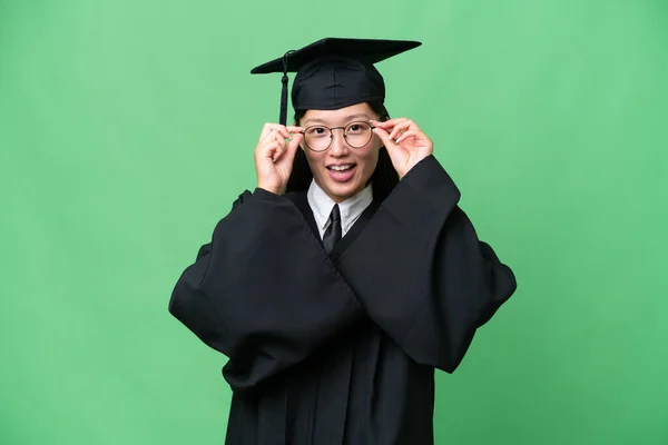 Young university graduate Asian woman over isolated background with glasses and surprised