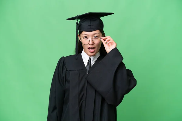 Young university graduate Asian woman over isolated background with glasses and surprised