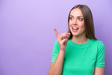Mor arka planda izole edilmiş genç beyaz kadın çözümü bulmak için parmağını kaldırıyor.