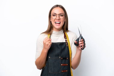 Young seamstress woman isolated on white background celebrating a victory in winner position