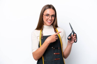 Young seamstress woman isolated on white background pointing to the side to present a product