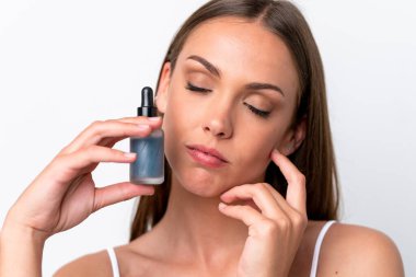 Beyaz arka planda izole edilmiş beyaz bir kadın elinde bir serum tutuyor. Portreyi kapat