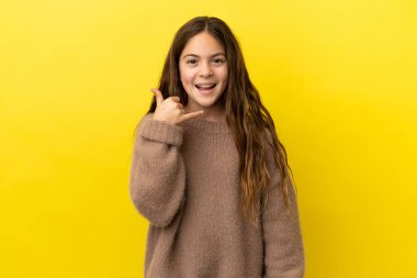 Sarı arka planda izole edilmiş küçük beyaz kız telefon jesti yapıyor. Bana geri dönüş işareti ver.