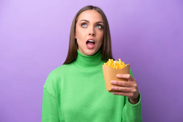 Young Caucasian Woman Holding Fried Chips Purple Background Looking Surprised — Stockfoto