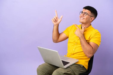 Dizüstü bilgisayarı işaret eden bir sandalyede oturan genç adam harika bir fikir.