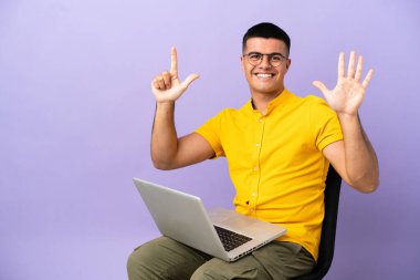 Young man sitting on a chair with laptop counting seven with fingers