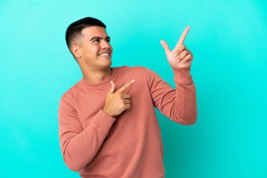 İzole edilmiş mavi arka planda genç yakışıklı adam işaret parmağıyla işaret etmek harika bir fikir.