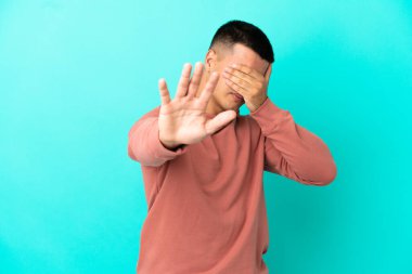 Young handsome man over isolated blue background making stop gesture and covering face