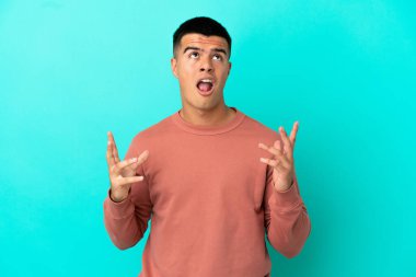 Soyutlanmış mavi arka planda genç yakışıklı bir adam stresli