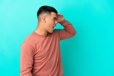 Soyutlanmış mavi arka planı olan genç yakışıklı bir adam.