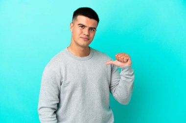 Genç yakışıklı, soyutlanmış mavi arka plan gururlu ve kendini beğenmiş.