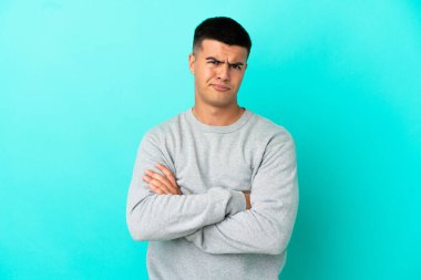 Young handsome man over isolated blue background feeling upset