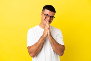 Soyutlanmış sarı arka planda genç yakışıklı bir adam avuç içlerini bir arada tutuyor. İnsan bir şey ister.