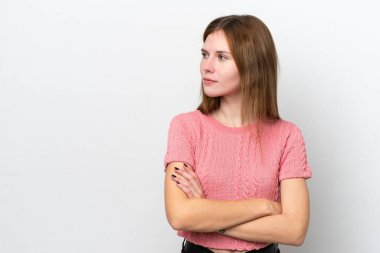 Beyaz arka planda izole edilmiş genç bir İngiliz kadın yan tarafa bakıyor.