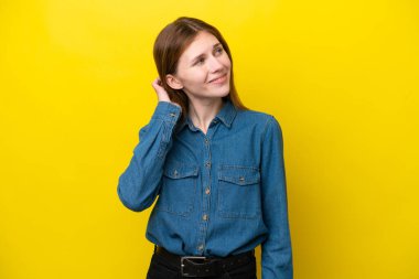 Sarı arka planda izole edilmiş genç bir İngiliz kadın bir fikir düşünüyor.