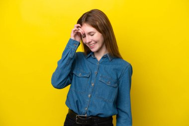 Sarı arka planda yalnız yaşayan genç İngiliz kadın gülüyor.