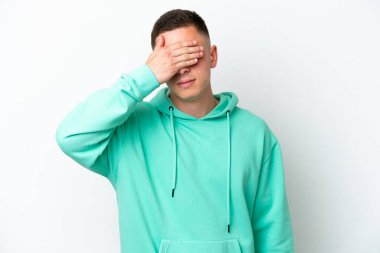 Genç Brezilyalı adam beyaz arka planda izole edilmiş, gözleri elle kaplanmış. Bir şey görmek istemiyorum.