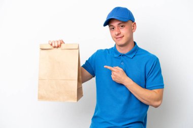 Young Brazilian man taking a bag of takeaway food isolated on white background pointing finger to the side