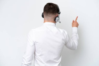 Telemarketer Brazilian man working with a headset isolated on white background pointing back with the index finger