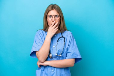 Mavi arka planda izole genç cerrah kadın şaşırmış ve şaşırmış görünüyor.