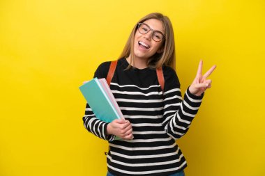 Young student woman isolated on yellow background background smiling and showing victory sign